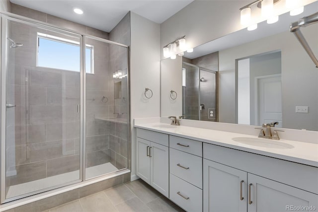 full bath featuring a sink, double vanity, a shower stall, and tile patterned flooring