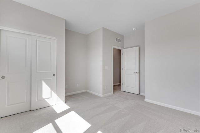 unfurnished bedroom featuring baseboards, a closet, visible vents, and light colored carpet