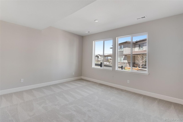 unfurnished room with baseboards, visible vents, and light colored carpet