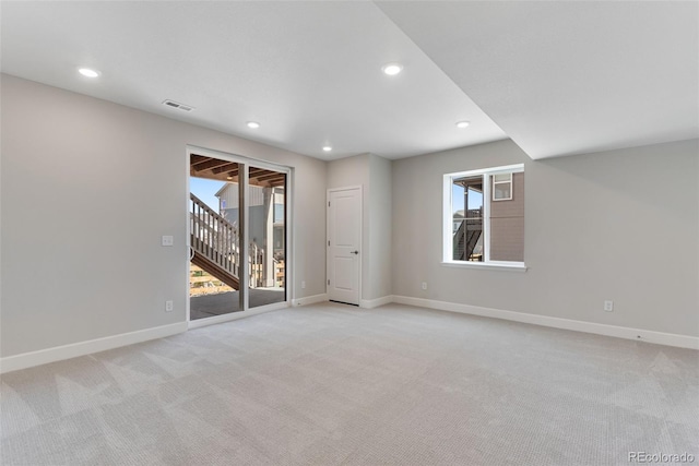 empty room featuring baseboards, visible vents, and light colored carpet