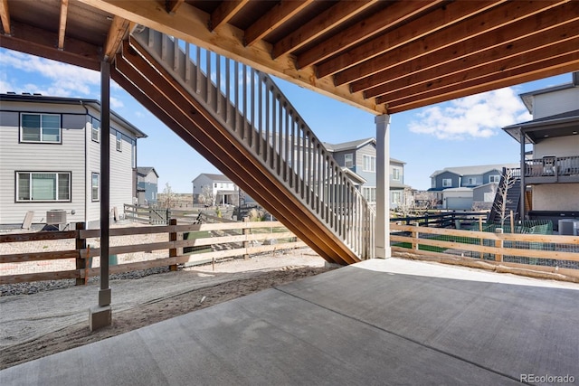view of patio / terrace featuring central air condition unit, stairway, a residential view, and fence