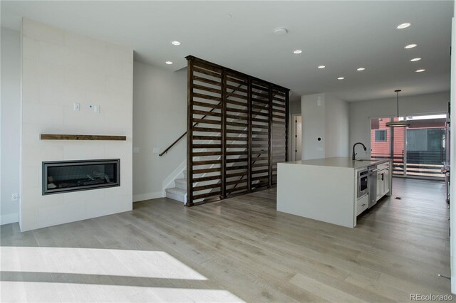 kitchen featuring sink, light wood-type flooring, hanging light fixtures, and white cabinets