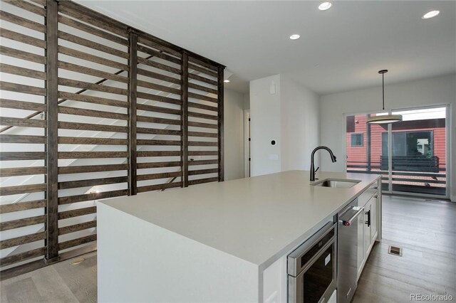 kitchen featuring white cabinets, pendant lighting, light hardwood / wood-style floors, and sink