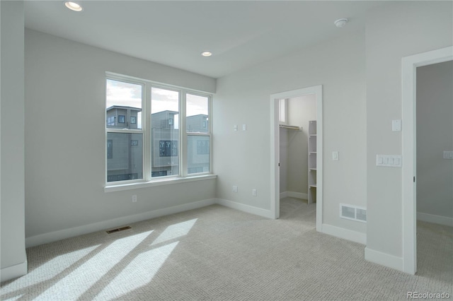 unfurnished bedroom featuring a closet, a spacious closet, and light colored carpet