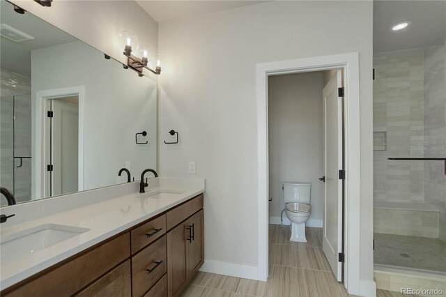 bathroom featuring a shower with shower door, toilet, tile patterned floors, and double sink vanity