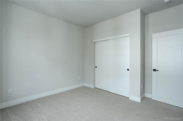 unfurnished bedroom with light carpet and a closet