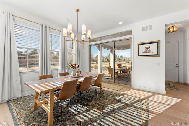 dining room featuring baseboards, visible vents, an inviting chandelier, and wood finished floors