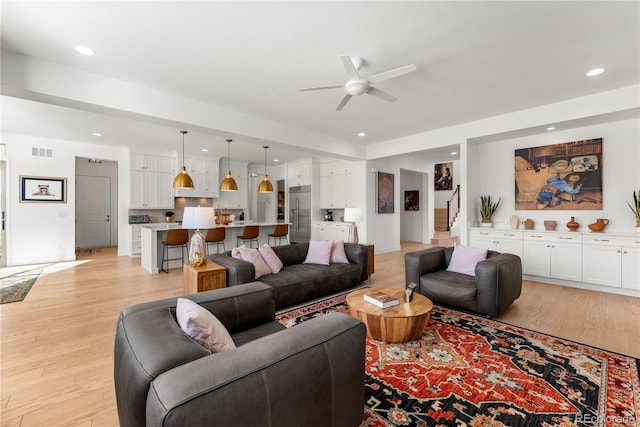 living area with recessed lighting, visible vents, stairway, light wood-style flooring, and a ceiling fan