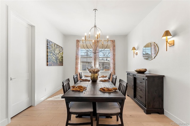 dining room featuring a chandelier, light wood finished floors, and baseboards