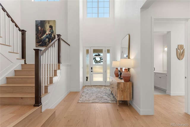 foyer featuring light wood-type flooring, a high ceiling, and stairs