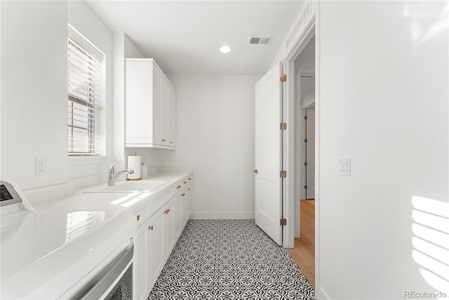 clothes washing area featuring cabinet space, visible vents, baseboards, a sink, and recessed lighting