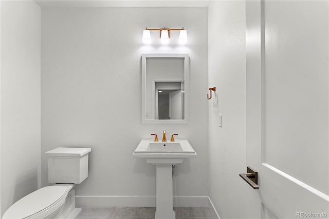 half bathroom featuring toilet, tile patterned flooring, and baseboards