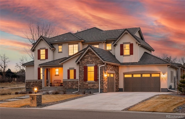 view of front of home featuring stucco siding, concrete driveway, a garage, stone siding, and a tiled roof