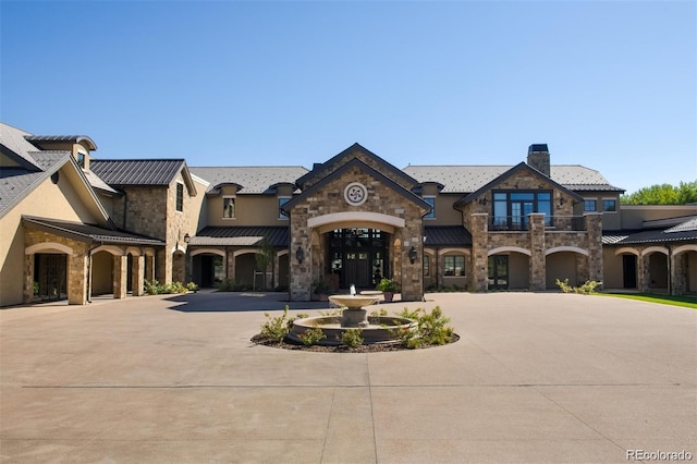 15 Latigo Pl, Littleton, CO 80123 - french country inspired facade featuring stone siding, curved driveway, and a chimney