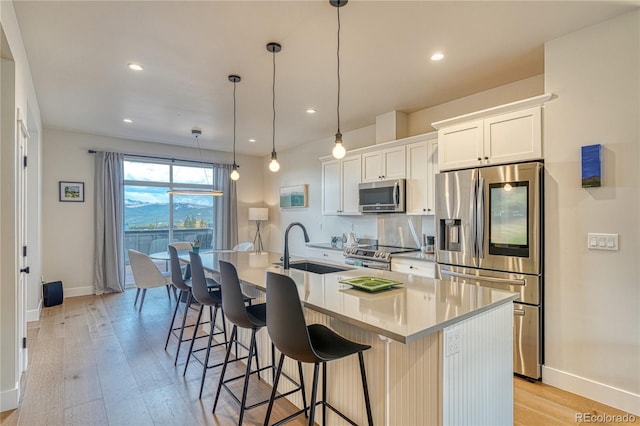 kitchen with white cabinets, a kitchen island with sink, stainless steel appliances, and sink