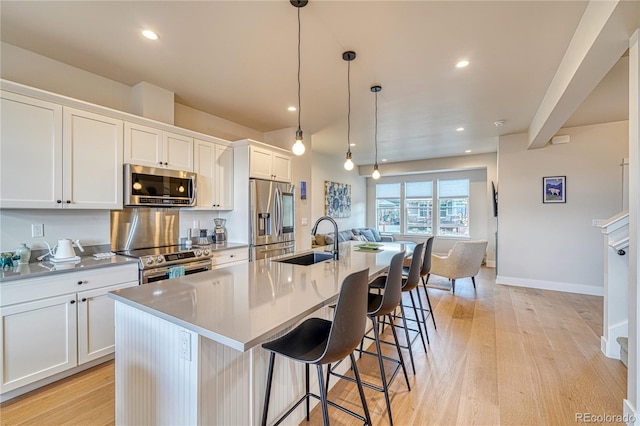 kitchen featuring pendant lighting, a center island with sink, appliances with stainless steel finishes, and sink