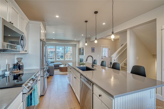 kitchen with a large island, white cabinetry, light hardwood / wood-style floors, and appliances with stainless steel finishes