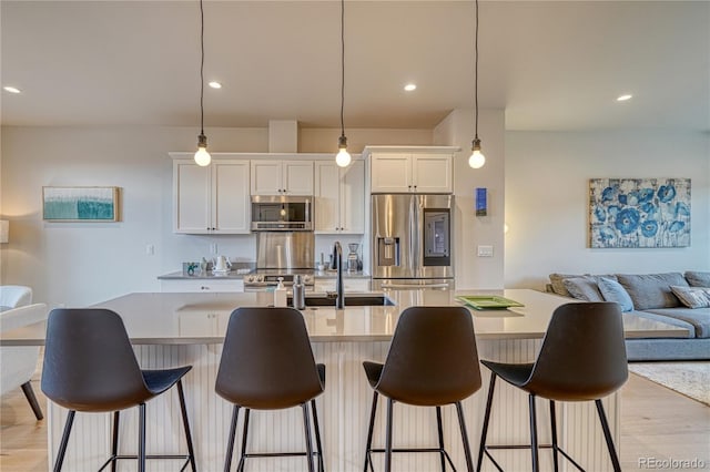 kitchen featuring white cabinets, appliances with stainless steel finishes, and decorative light fixtures