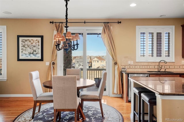 dining space with light hardwood / wood-style floors, sink, and a notable chandelier