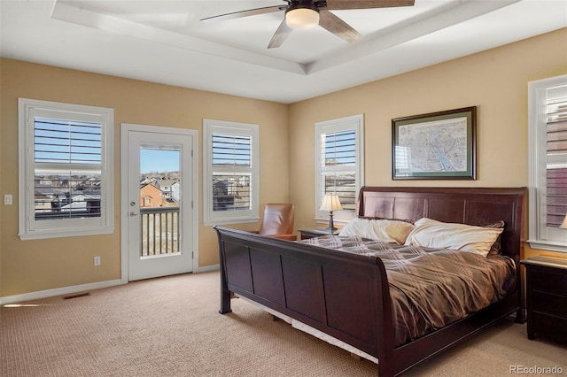 carpeted bedroom with ceiling fan, a tray ceiling, and access to outside