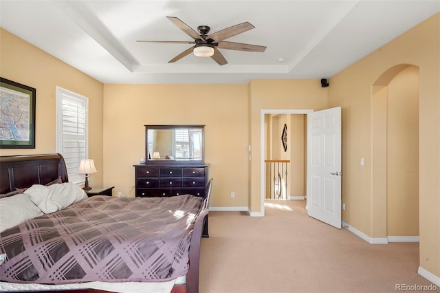 bedroom featuring light colored carpet, ceiling fan, and a tray ceiling