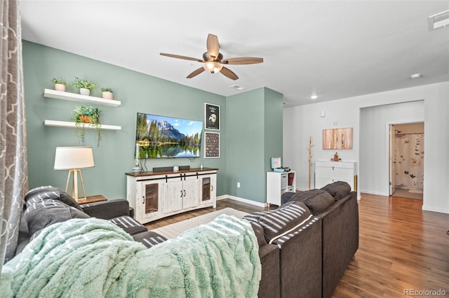 living area featuring a ceiling fan, visible vents, baseboards, and wood finished floors