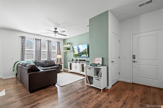 living room featuring ceiling fan, dark wood-type flooring, visible vents, and baseboards