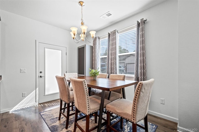 dining space with dark wood-style floors, visible vents, a notable chandelier, and baseboards