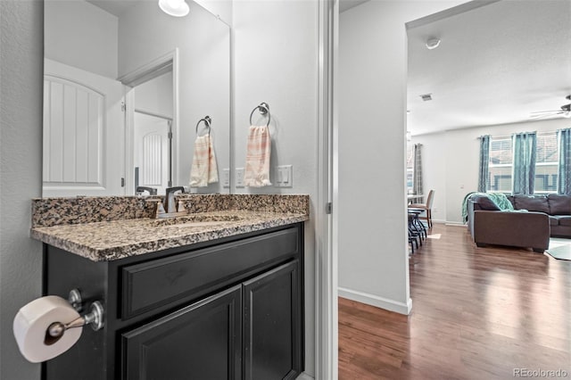 bathroom with visible vents, a ceiling fan, vanity, wood finished floors, and baseboards