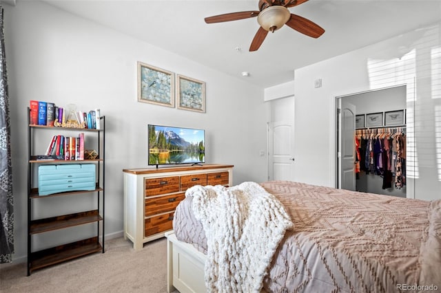 bedroom with a ceiling fan, a walk in closet, a closet, and light carpet