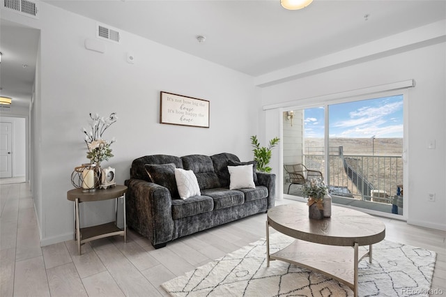 living room featuring baseboards, visible vents, and light wood finished floors