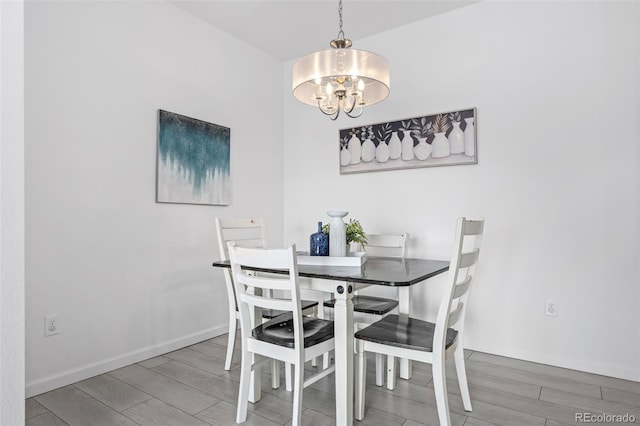 dining area featuring wood finish floors, baseboards, and an inviting chandelier