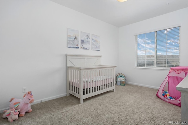 bedroom with baseboards, a crib, and carpet flooring