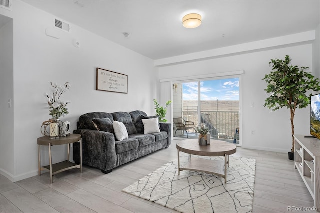 living room with light wood-style floors, visible vents, and baseboards