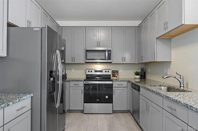 kitchen with gray cabinets, appliances with stainless steel finishes, and a sink