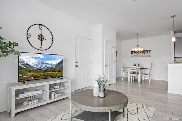 living room featuring baseboards, light wood-style floors, and an inviting chandelier