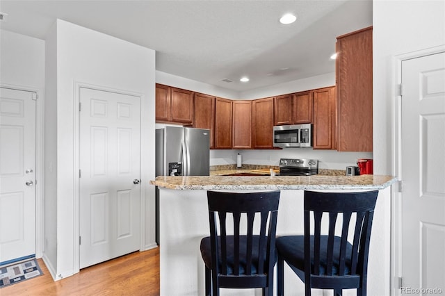 12753 Leyden St Unit C, Thornton, CO 80602 - kitchen featuring stainless steel appliances, a breakfast bar area, recessed lighting, light wood-style floors, and a peninsula