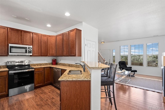 12753 Leyden St Unit C, Thornton, CO 80602 - kitchen featuring appliances with stainless steel finishes, a breakfast bar area, a peninsula, dark wood-style flooring, and recessed lighting