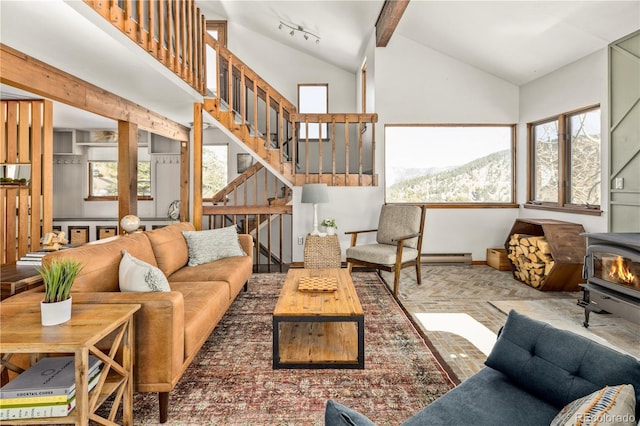 living room with a mountain view, high vaulted ceiling, a healthy amount of sunlight, and a wood stove