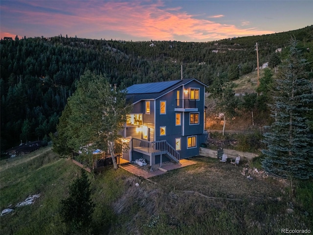 back house at dusk with a balcony and a deck