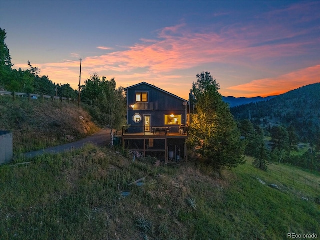 back house at dusk with a deck with mountain view