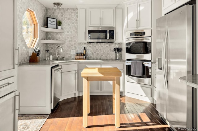 kitchen featuring tasteful backsplash, light stone counters, wood-type flooring, appliances with stainless steel finishes, and white cabinets