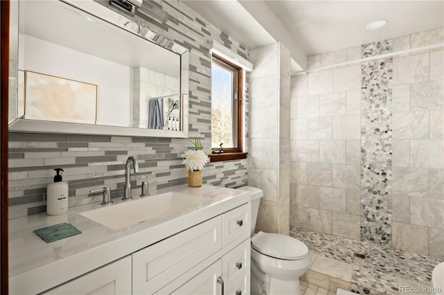 bathroom with vanity, a tile shower, backsplash, and toilet