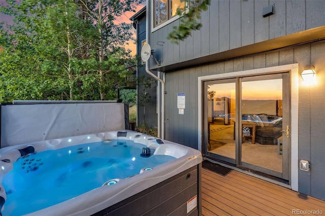 deck at dusk featuring a hot tub