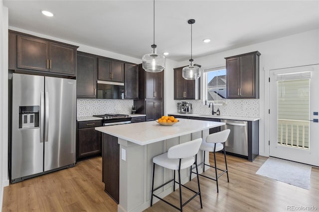 175 Westerly Blvd, Erie, CO 80516 - kitchen featuring appliances with stainless steel finishes, dark brown cabinetry, light wood-style floors, a kitchen breakfast bar, and a kitchen island