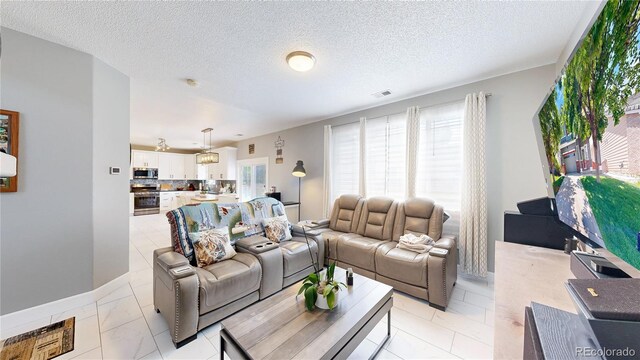 19730 E 58th Pl, Aurora, CO 80019 - living room featuring light marble finish flooring, baseboards, and a textured ceiling