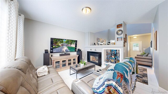 19730 E 58th Pl, Aurora, CO 80019 - living room with a glass covered fireplace, a textured ceiling, and baseboards