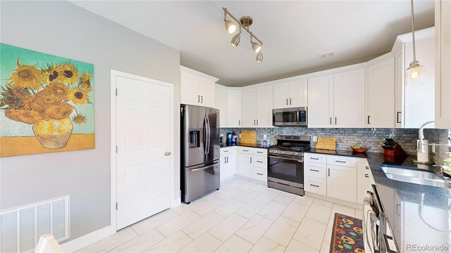 19730 E 58th Pl, Aurora, CO 80019 - kitchen featuring appliances with stainless steel finishes, a sink, tasteful backsplash, white cabinetry, and dark stone countertops