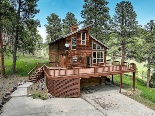 13190 Coyote Song Trl, Conifer, CO 80433 - view of front of home with concrete driveway, a deck, a chimney, and a carport