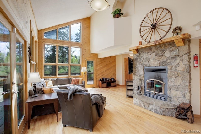 13190 Coyote Song Trl, Conifer, CO 80433 - living room featuring a stone fireplace, plenty of natural light, high vaulted ceiling, wood finished floors, and wood walls